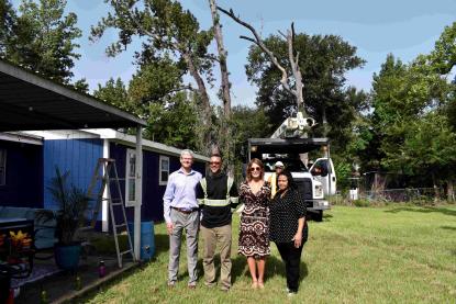 4 people standing in front of tree being cut down