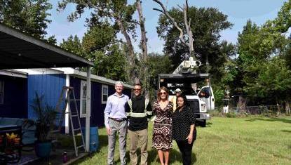 4 people in front of tree being cut down